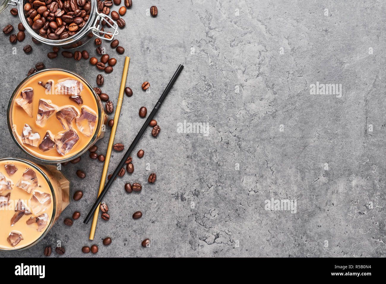 Schokolade, Vanille, Karamell oder Zimt Eiskaffee im großen Glas. Kalt Eiskaffee in Glas und Kaffeebohnen in Glas Glas auf grauem Beton bac gebraut Stockfoto