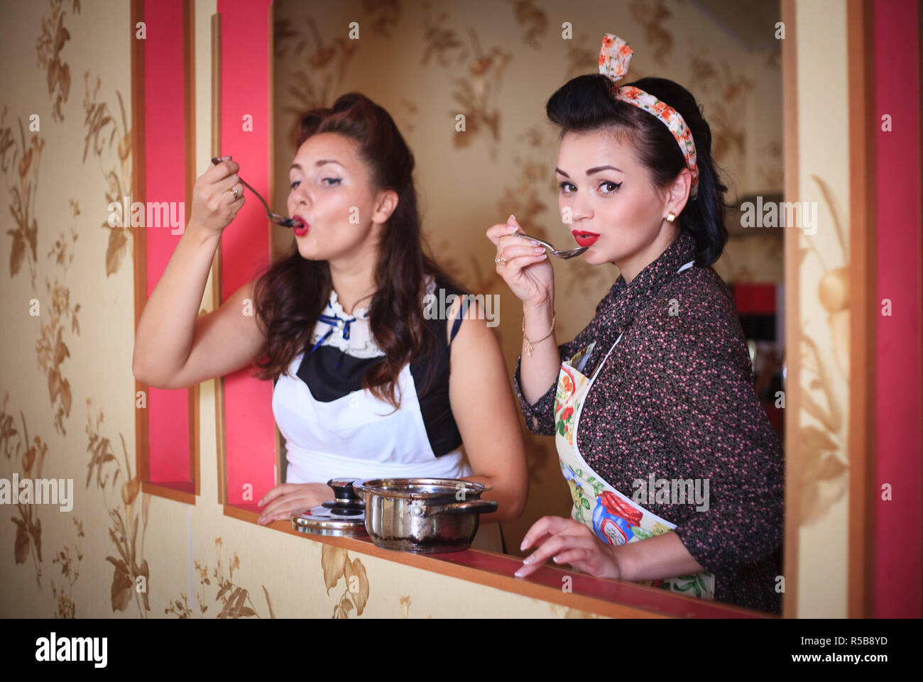 Zwei Frauen in der Küche zubereiten und essen schmeckt. Retro Style. Haushalt Konzept. Stockfoto