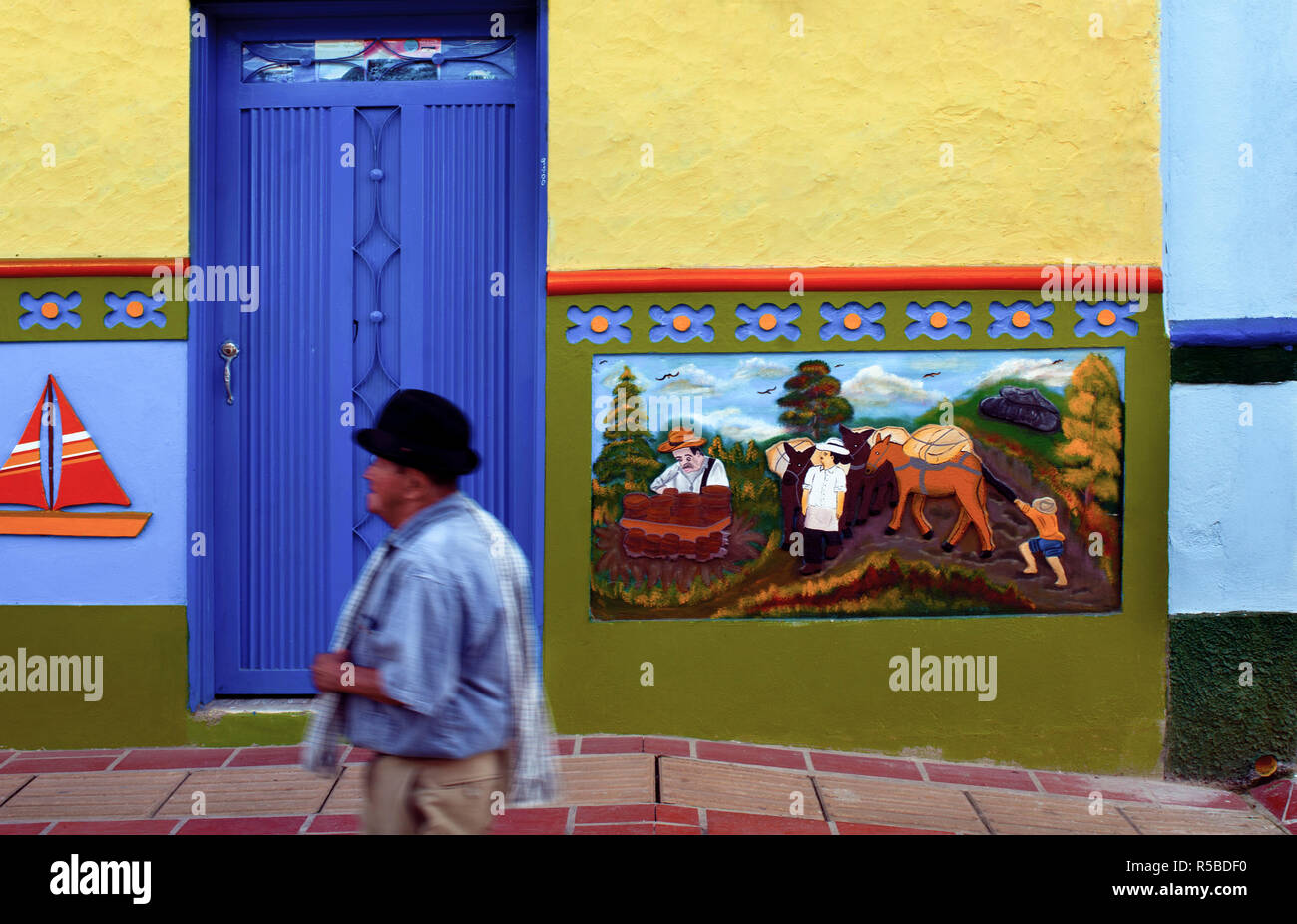 Guatape, Kolumbien, touristische Ziel außerhalb von Medellin, lokalen Bewohner Tragen eines traditionellen Wolle' Ruana" (Kap) über der Schulter, kleine Stadt, die für Ihre "Zocalos', die handgemachte gemalten Tafeln der Dreidimensionalen Kunst, des bunten Wänden drapiert sind bekannt Stockfoto