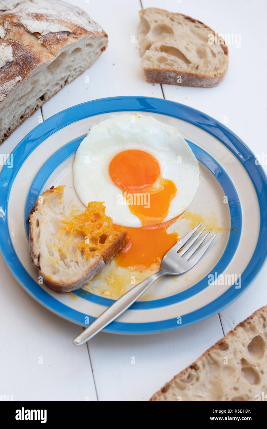 Gebratene Hühner Eier auf einem cornishware Platte mit Sauerteigbrot Stockfoto