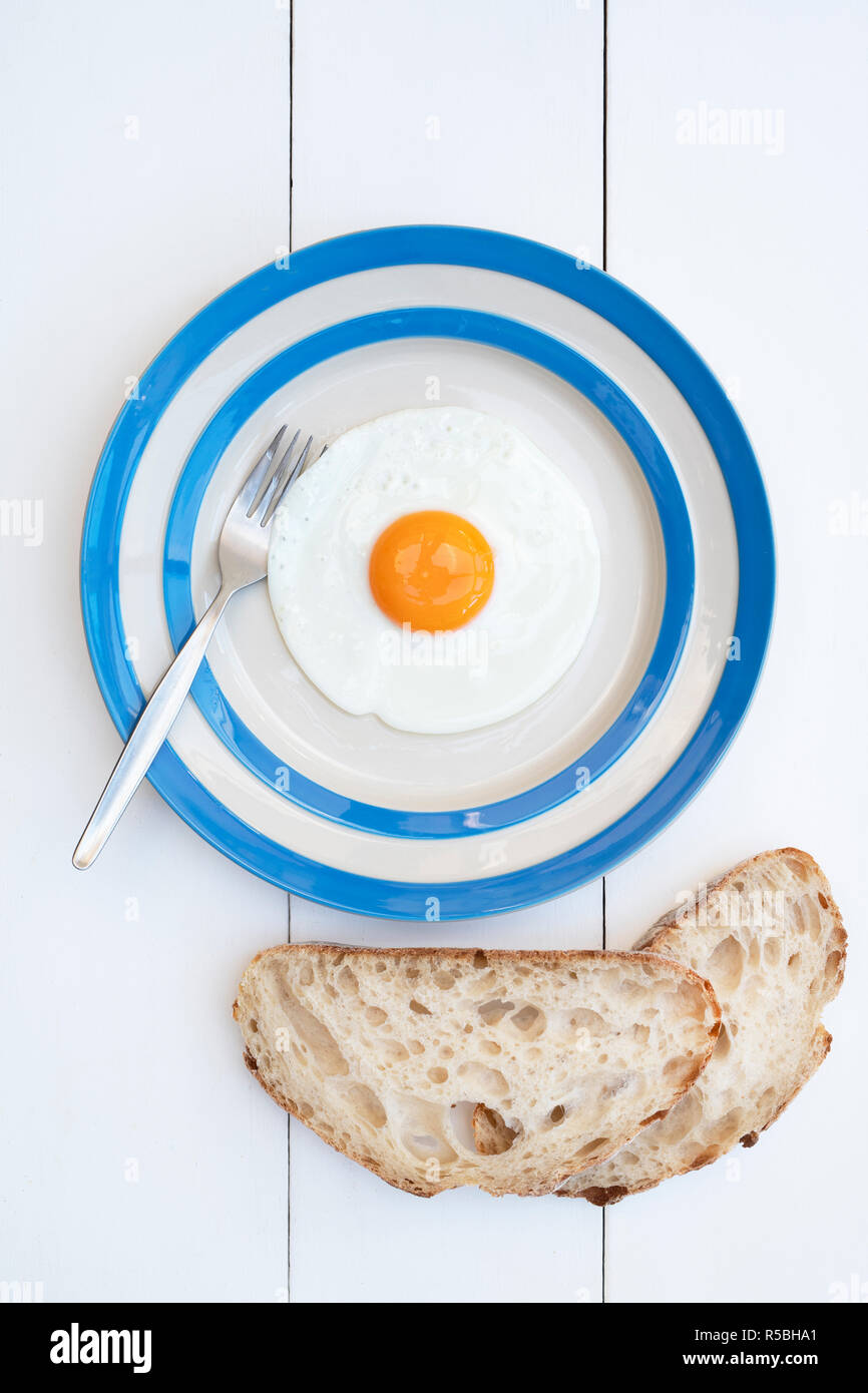 Gebratene Hühner Eier auf einem cornishware Platte mit Sauerteigbrot Stockfoto
