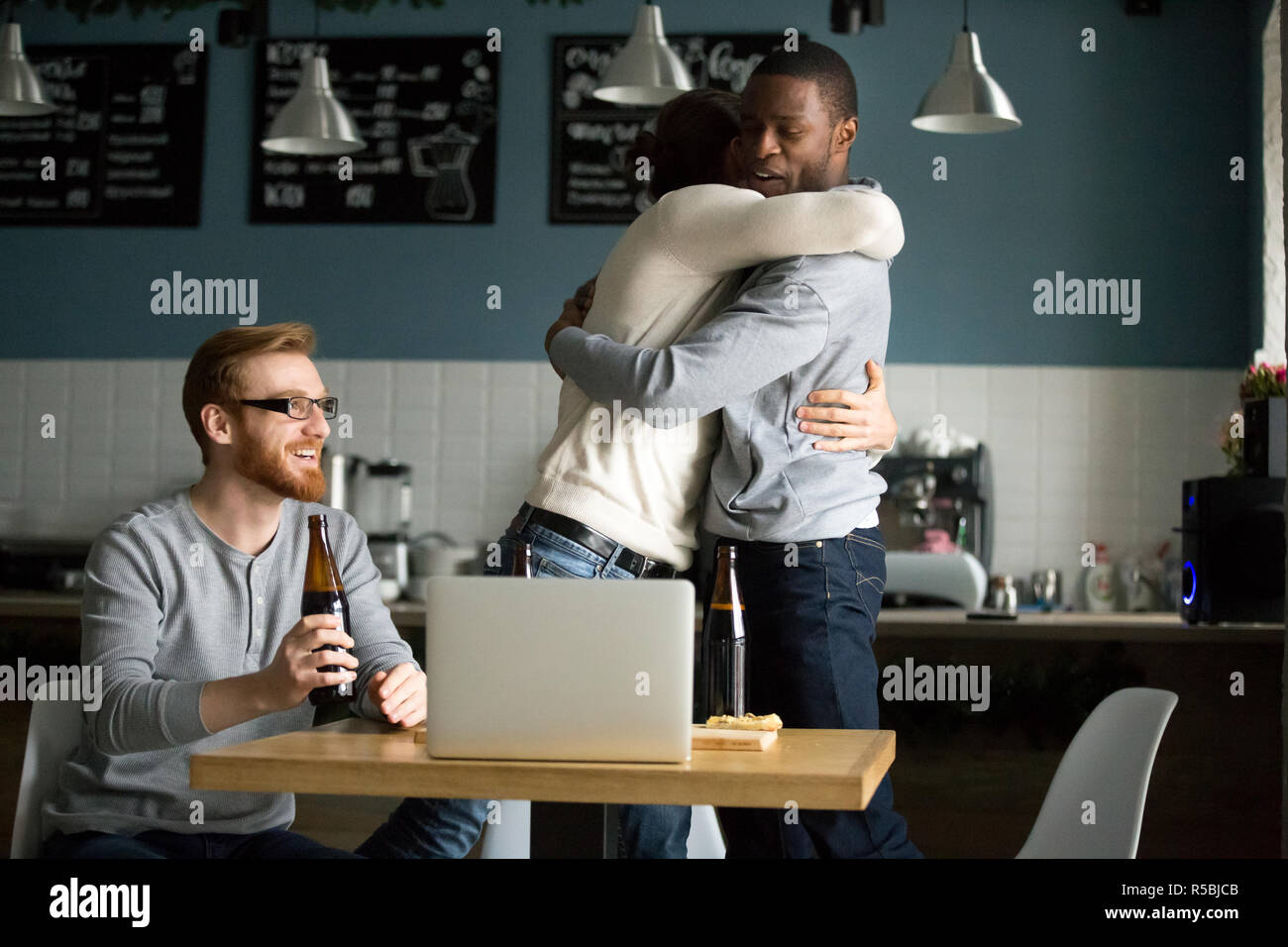 Happy multiethnischen Freunde Hug feiern Sieg in Kneipe hängen, aufgeregt, diverse Männer gratulieren mit Tor umarmen, Jungs haben Spaß Stockfoto