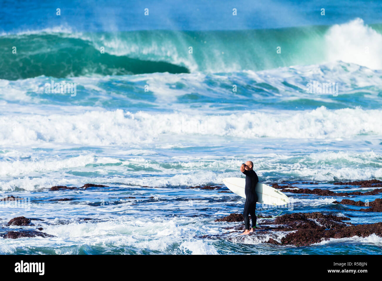 Surfer über in Ocean Wave, Rock Eintritt in Wasser zu springen surfen zu gehen. Stockfoto