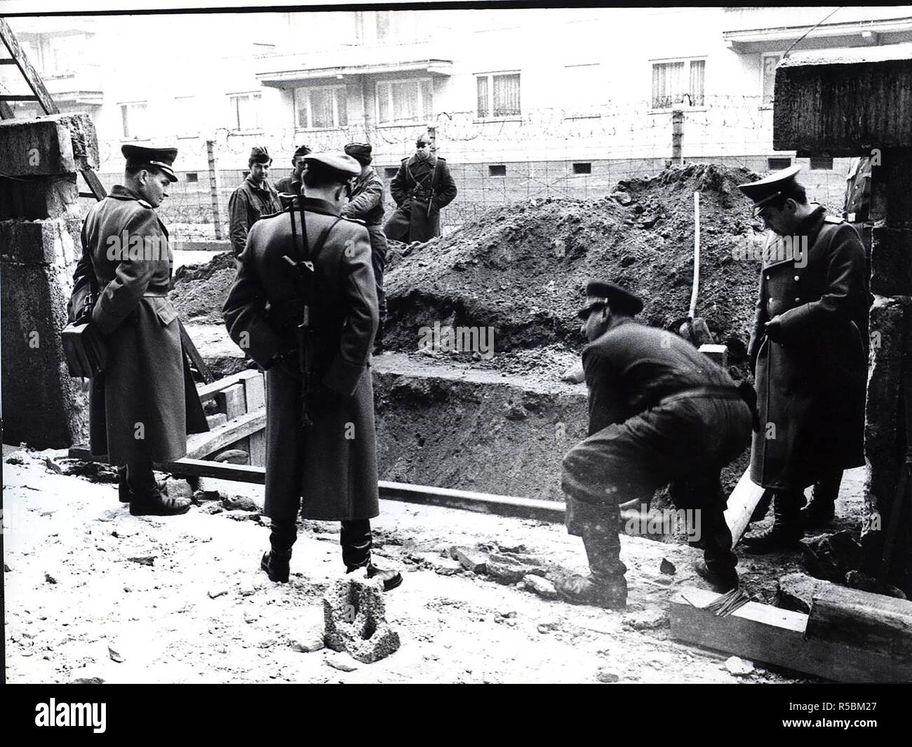 Weil eine Wasserleitung geplatzt Direkt unter der Wand eine Truppe der Volksarmy Arbeitnehmer in Berufen sind. Die Baustelle wurde durch den Höheren sowjetischen Offizieren bewacht Stockfoto