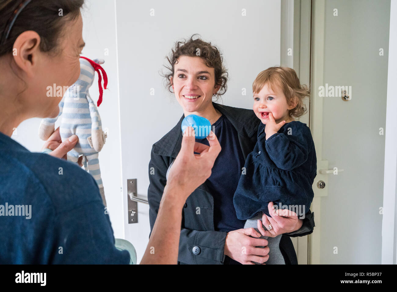 Eine Mutter nimmt ihr 16 Monate altes Baby Mädchen zu einem Baby caregiver. Stockfoto