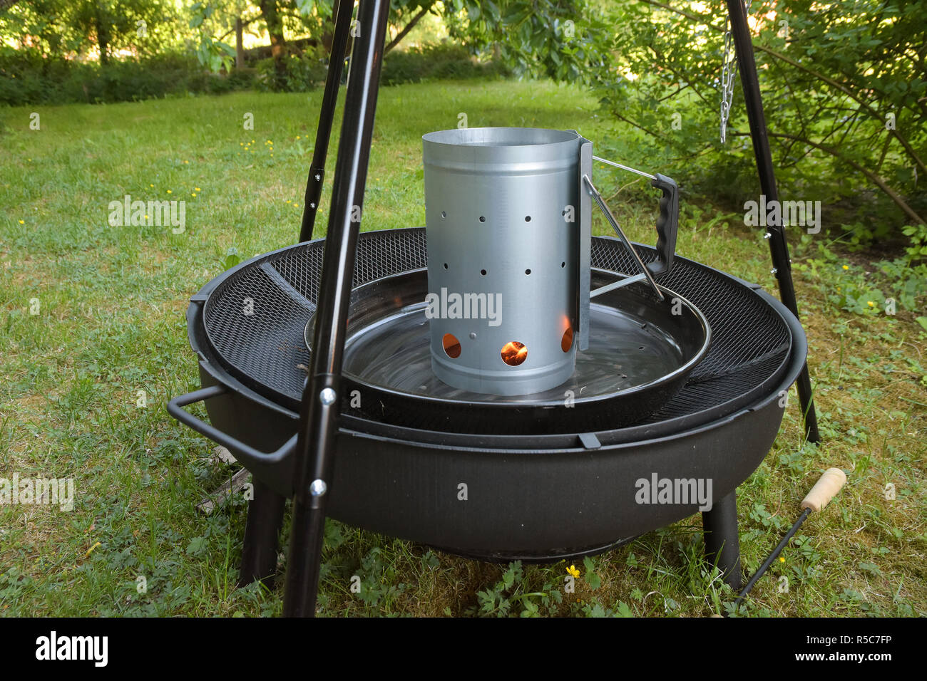 Grill Holzkohle Chimney Starter auf einem schwarzen Stativ schwenken Grill im Garten Stockfoto