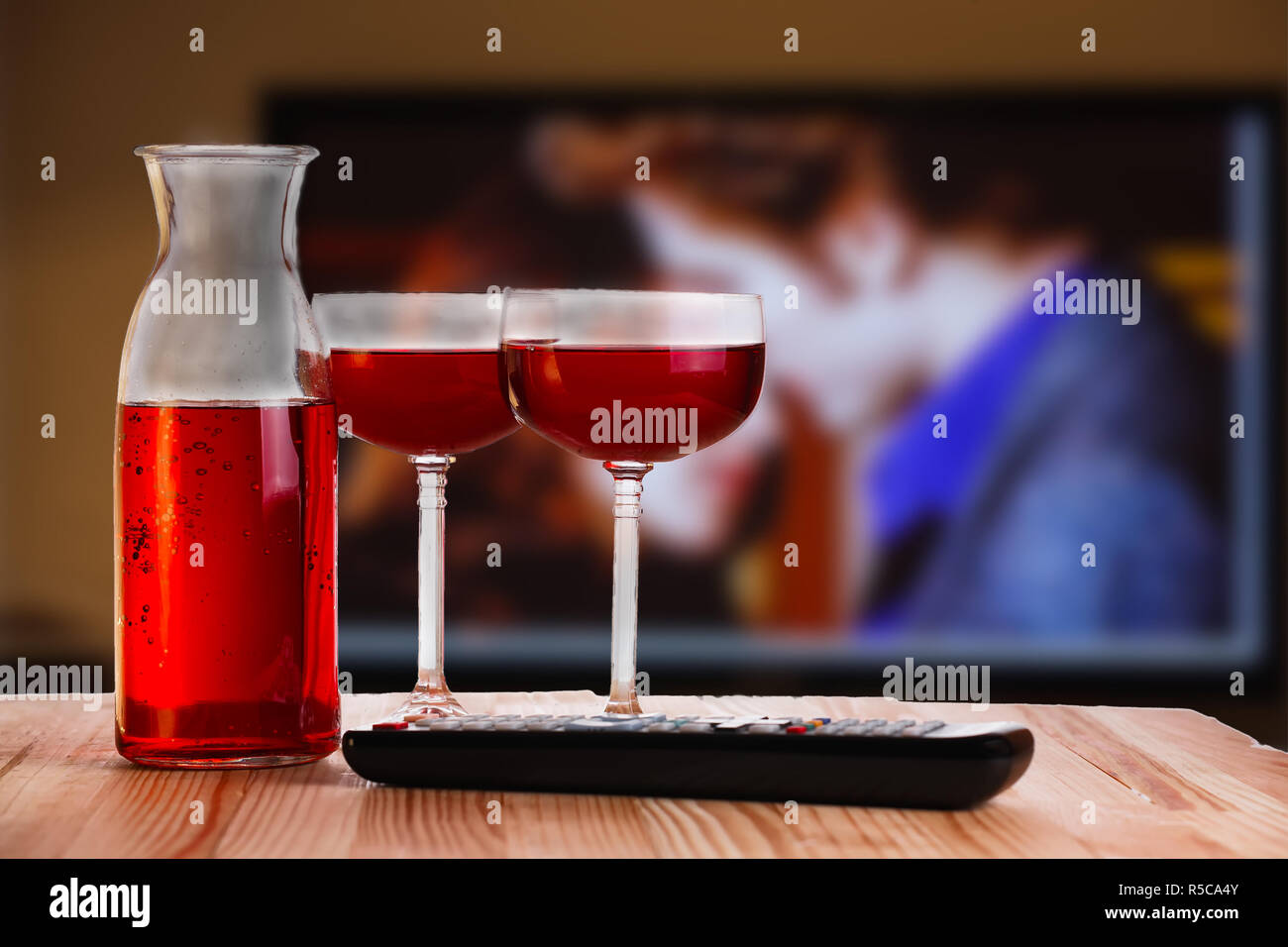 Zwei Glas und Karaffe Wein mit TV-Fernbedienung auf hellen, natürlichen hölzernen Tisch. Konzept der romantischen Film ansehen. Stockfoto