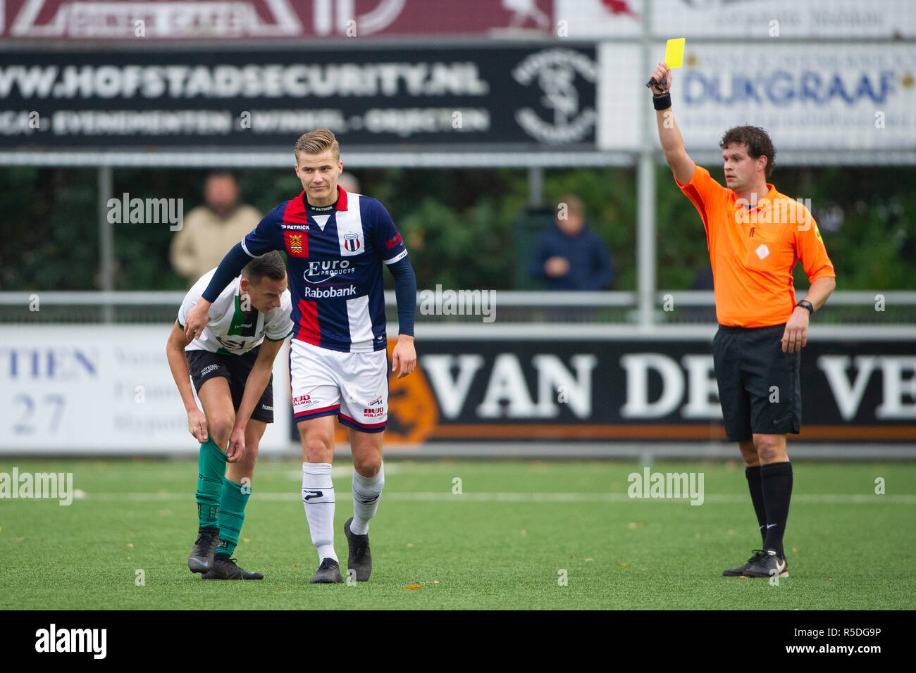 Niederlande. 1. Dezember 2018. DEN HAAG, 01-12-2018, Fußball, Sportpark Houtrust, Saison 2018 / 2019, Niederländische Tweede Divisie. Excelsior Maassluis Spieler Kevin Dercks (m) erhält die Gelbe Karte von Schiedsrichter E. Thijs nach Foul auf Scheveningen Spieler Barry Rog während des Spiels Scheveningen vs Excelsior Maassluis (0-1) Credit: Pro Schüsse/Alamy leben Nachrichten Stockfoto