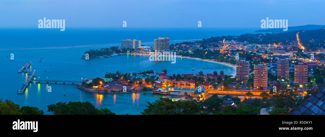 Erhöhte Aussicht auf Stadt und Küste leuchtet in der Dämmerung, Ocho Rios, Saint Ann Parish, Jamaika, Karibik Stockfoto