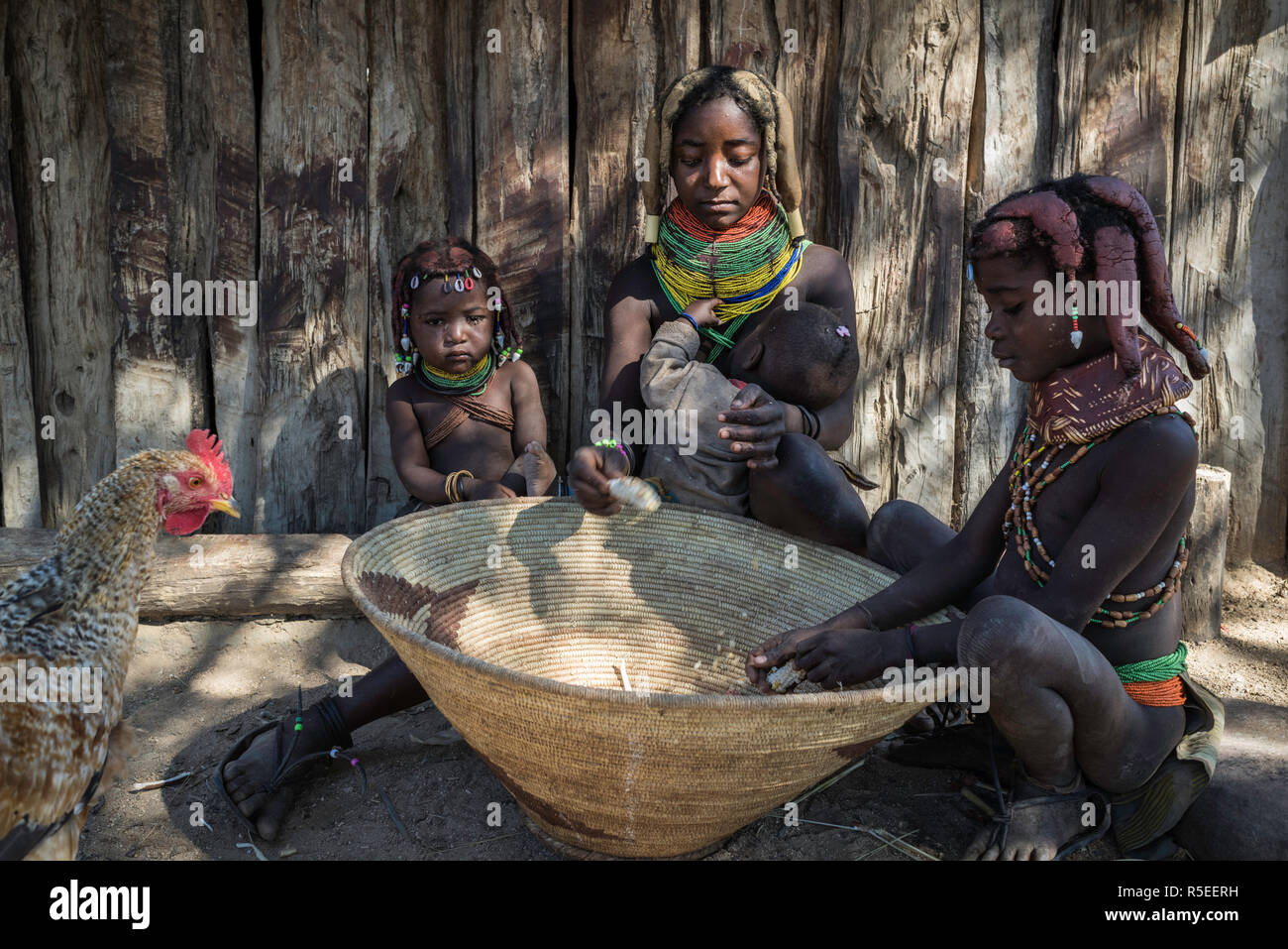 Muila Familie aus den Kernen der Mais in einem Korb, während ein Huhn zu suchen ist. Stockfoto