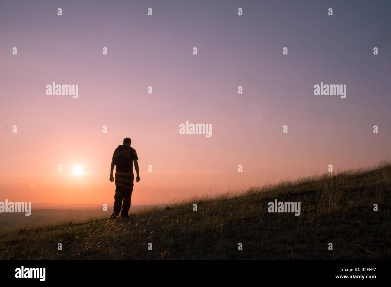 Die Silhouette eines einsamen Mann mit Rucksack zu Fuß auf einem Hügel. Stockfoto