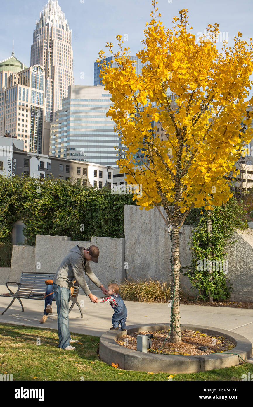 CHARLOTTE, NC - November 25, 2016: ein Vater spielt mit seinem jungen Sohn in Romare Bearden Park in Uptown Charlotte, North Carolina. Stockfoto