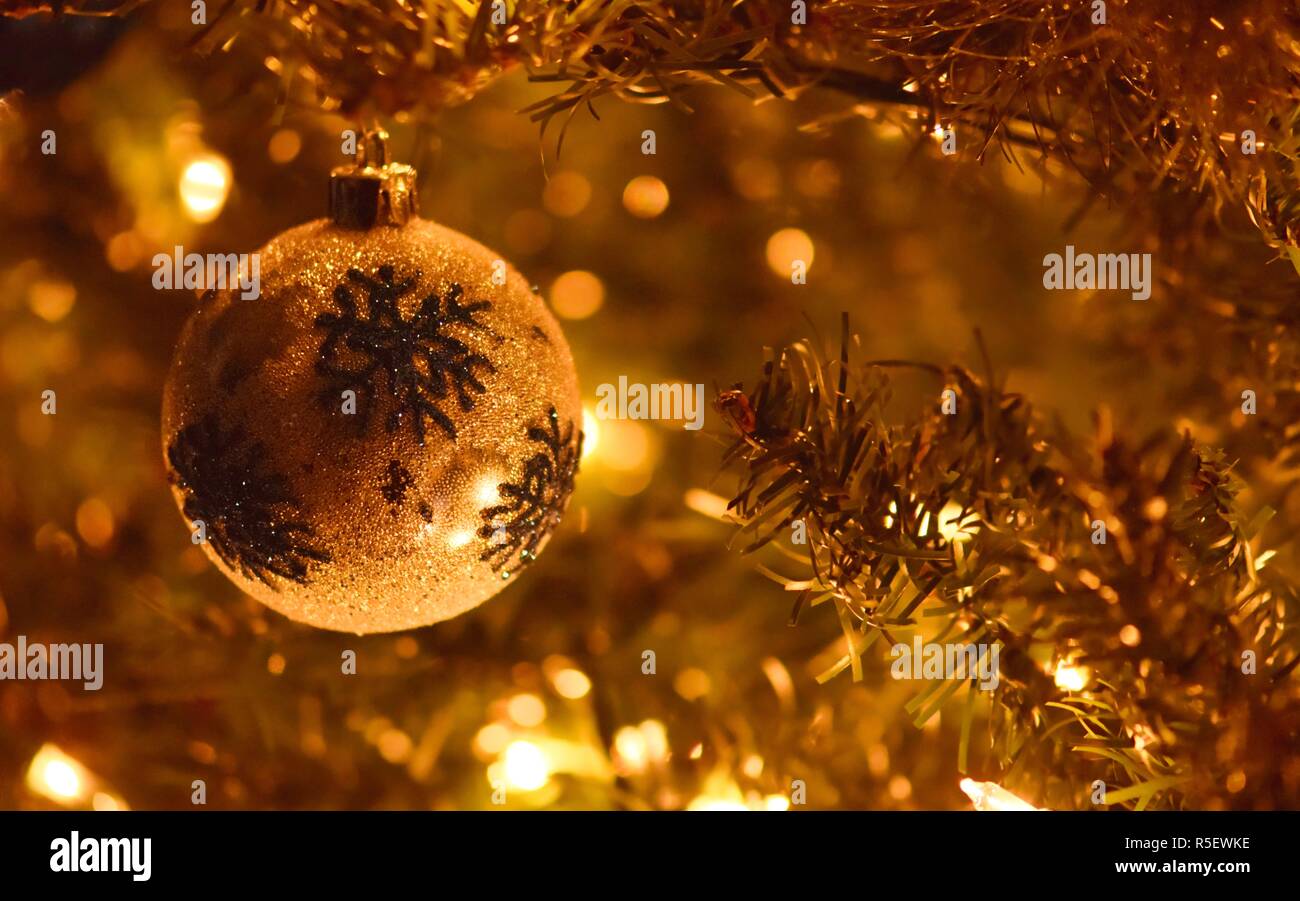 Nahaufnahme einer Weihnachtskugel hängen an einen Weihnachtsbaum mit einem schönen goldenen Glanz umhüllt das ganze Bild. Stockfoto