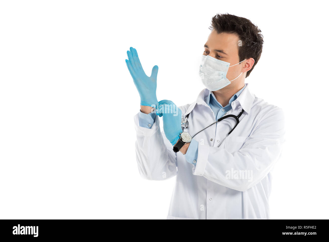 Stattliche männliche Arzt setzen auf Gummihandschuhe isoliert auf weißem Stockfoto