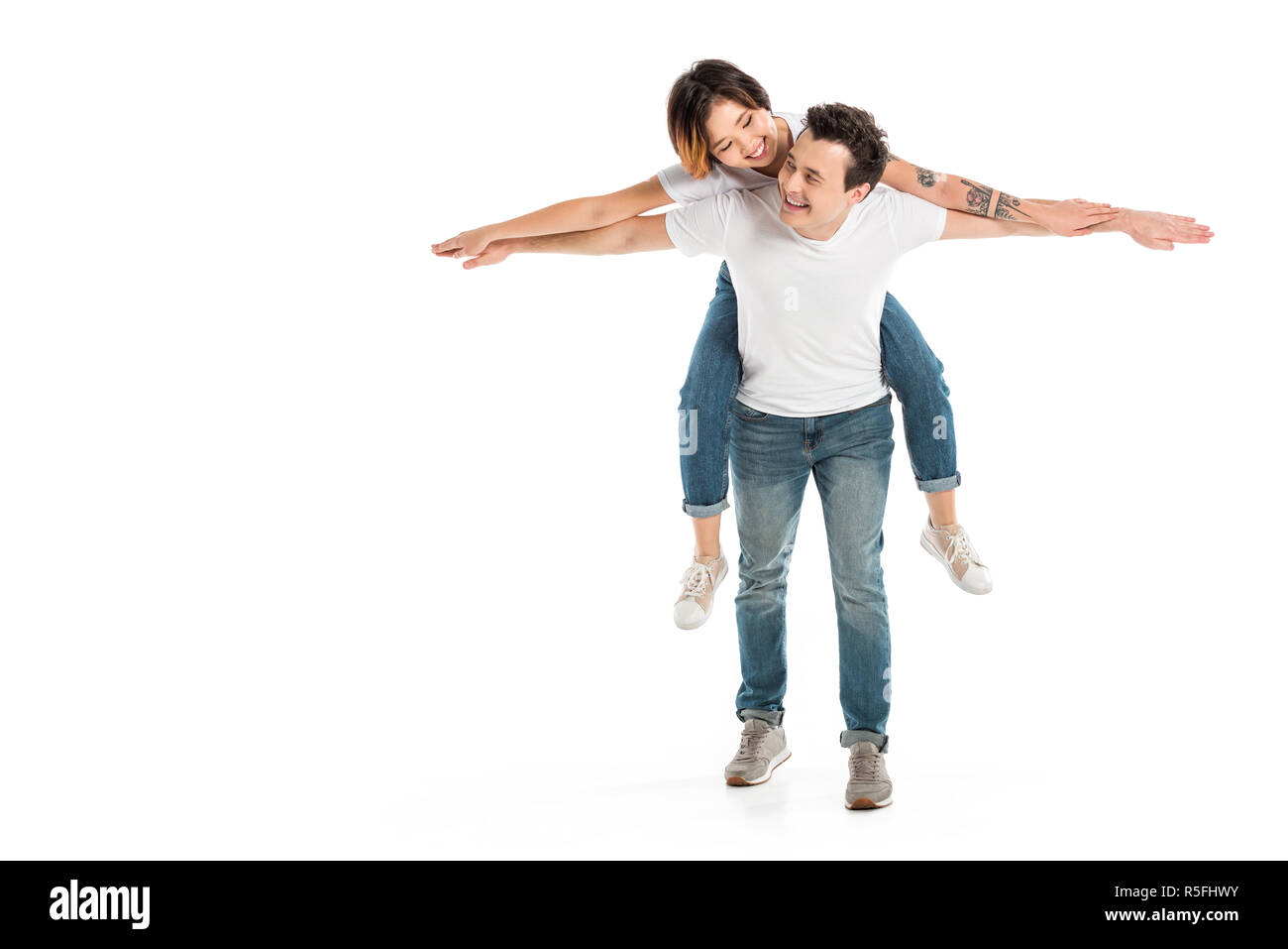 Gerne Mann und Frau piggyback Ride isoliert auf Weiss, paar Spaß Stockfoto