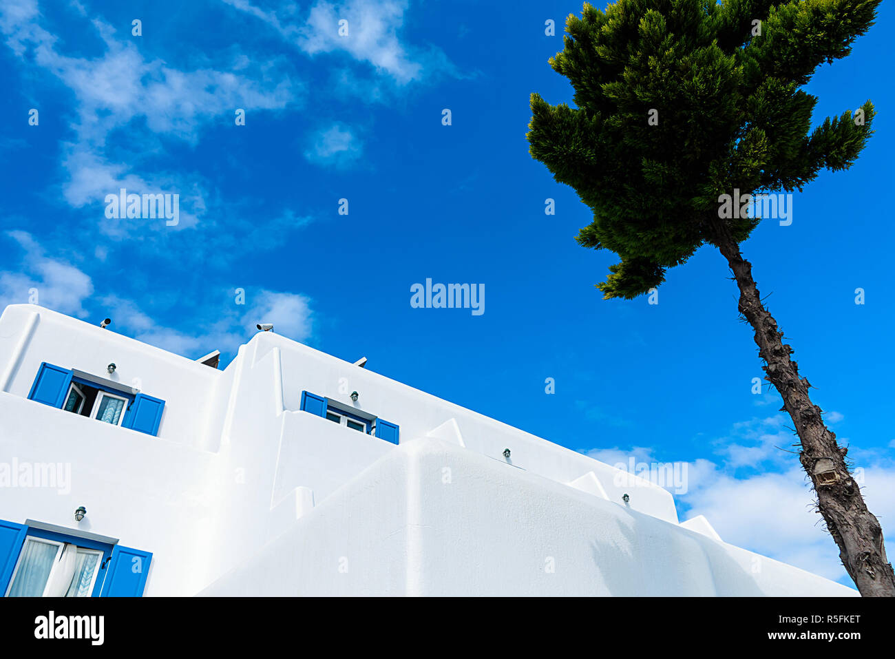 Weiß getünchtes Haus mit blauen Fensterläden auf der hellen Blau, Aegean Sky Stockfoto