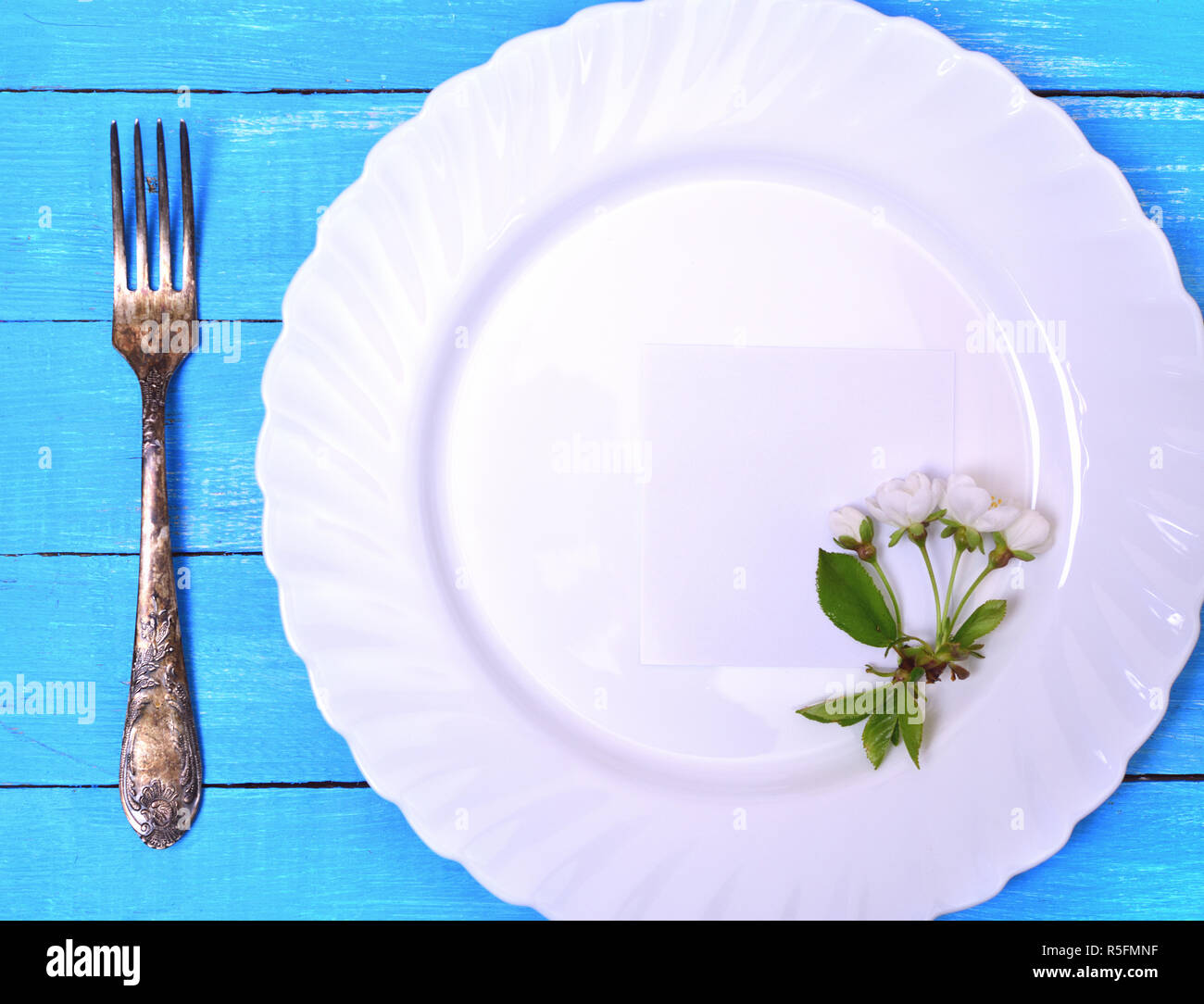 Weiße Platte mit einem Blatt Papier Stockfoto