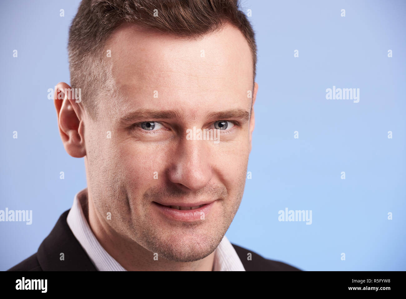 Portrait von lächelnden Mann in Anzug auf blauem Hintergrund Stockfoto