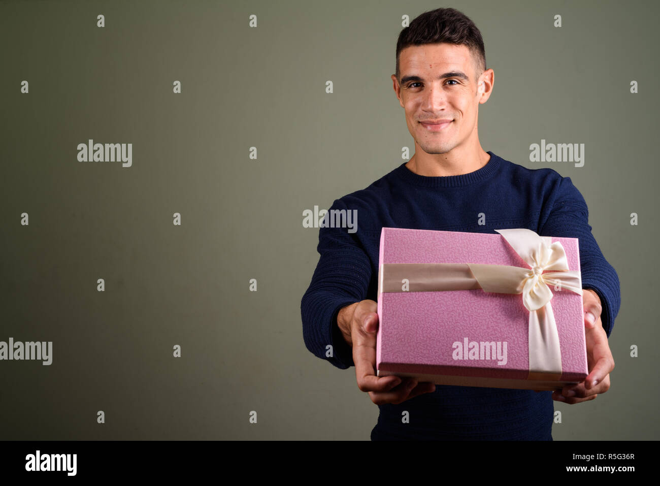Jungen gutaussehenden Mann mit Geschenkbox gegen farbigen Hintergrund Stockfoto
