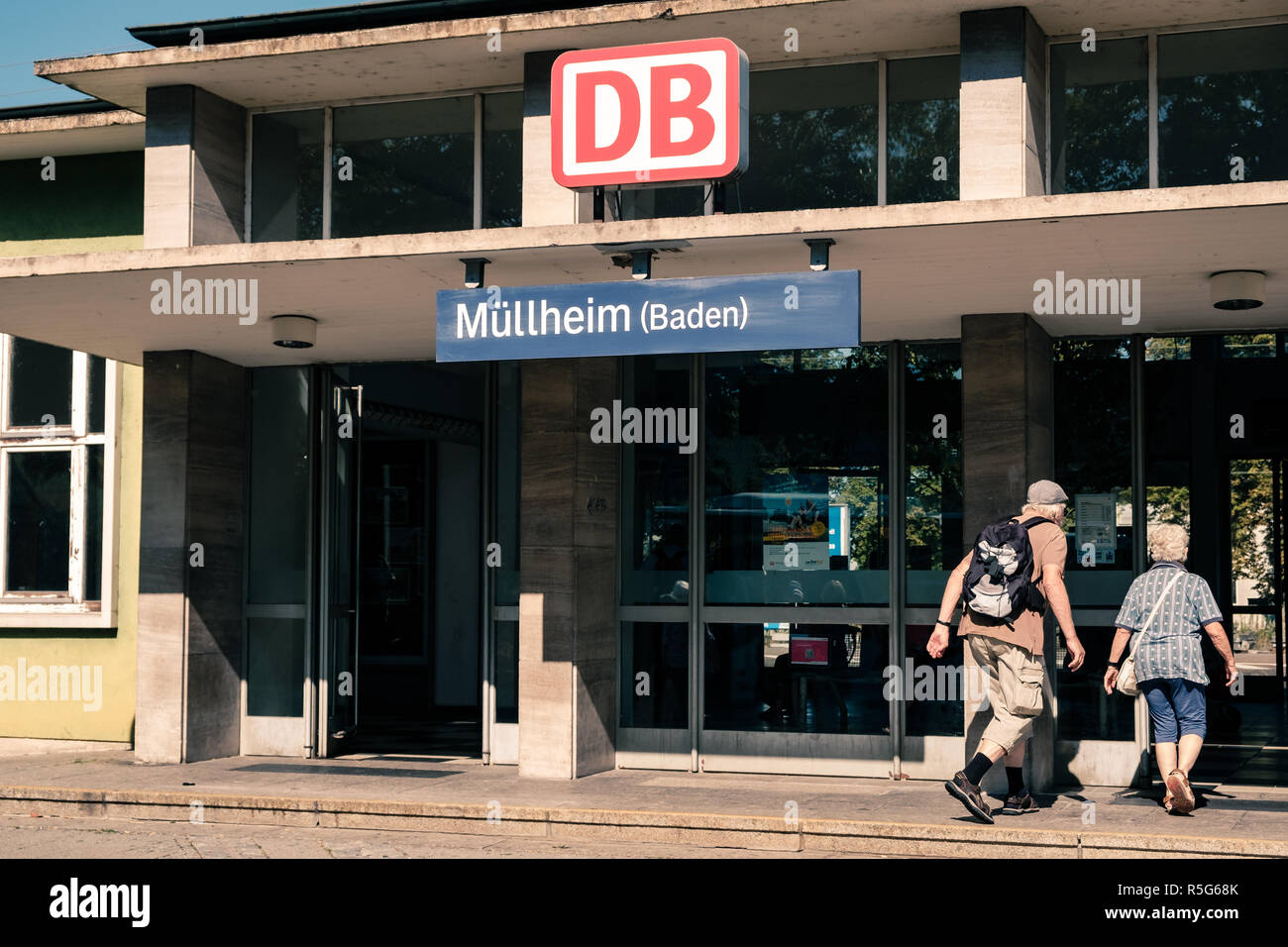 Mullheim, Baden-Württemberg, Deutschland - 30. JULI 2018: Senior paar Eingabe der Mullheim Bahnhof. Mann mit Rucksack. Region Südwest von Germ Stockfoto