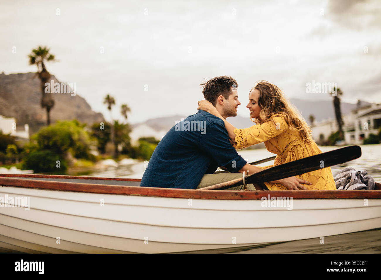 Seitliche Sicht auf ein Paar in einem Boot sitzen und reden miteinander. Paar in Liebe auf einem Boot Datum Sitzung zusammen halten. Stockfoto