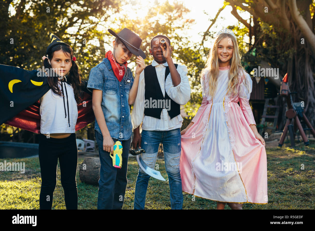 Gruppe von Kindern im Garten im Hinterhof stehen verschiedene Kostüm tragen. Jungen und Mädchen Spaß im Freien mit Superhelden Kostüme. Stockfoto