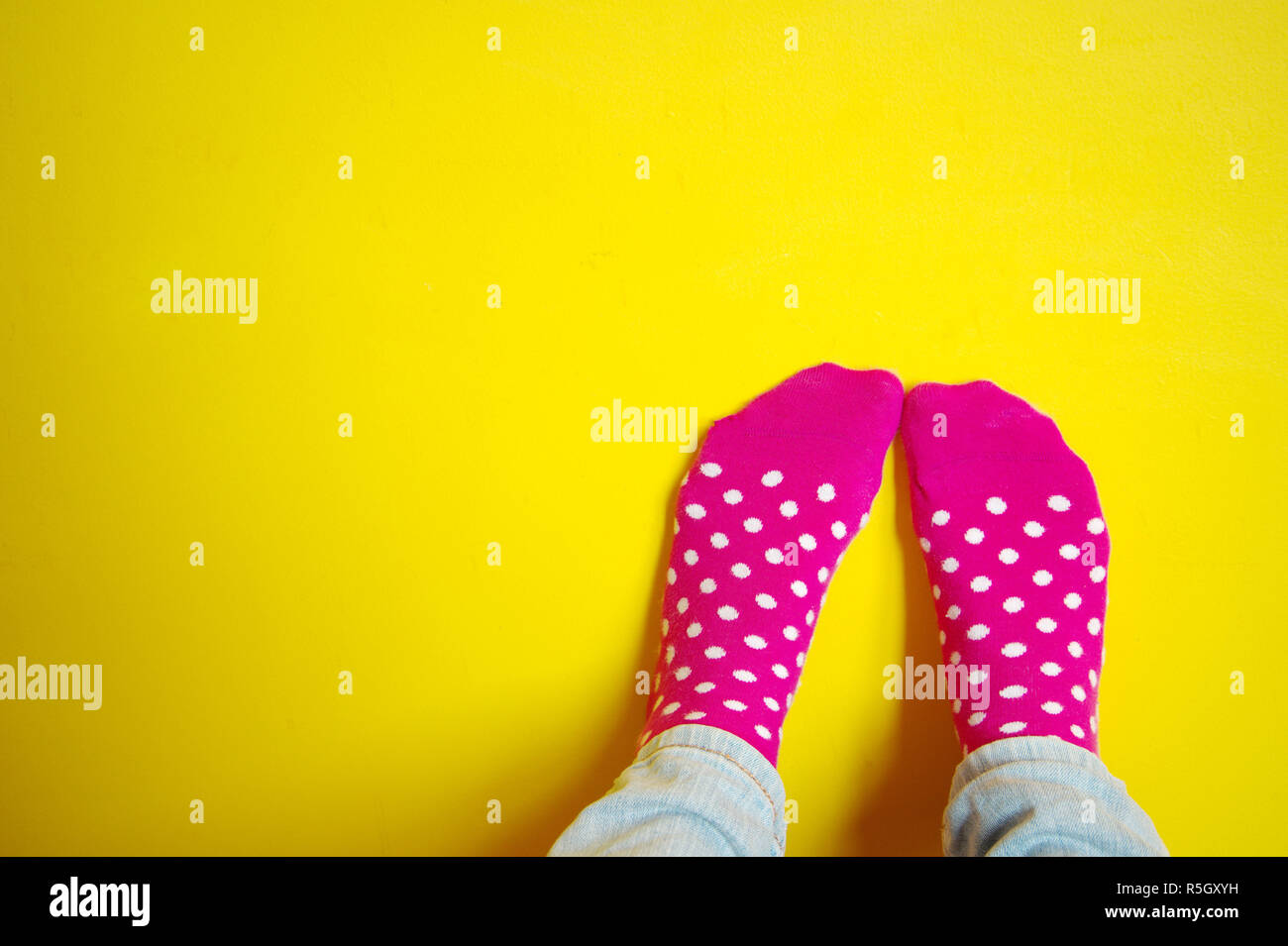 Bunte Schönheit niedlichen rosa Socke mit weissem Punkt mit Frauen Fuß auf gelb leuchtenden Hintergrund Stockfoto