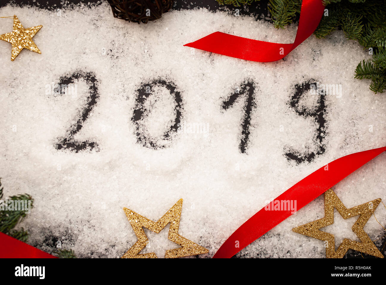 2019 im Schnee auf schwarzen Hintergrund mit grünen Zweigen und goldenen Sternen verziert geschrieben Stockfoto