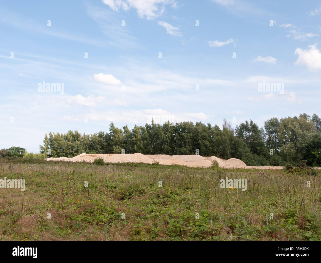 Stapel der Sand vom Steinbruch in der Nähe von Feld mit Himmel über Stockfoto