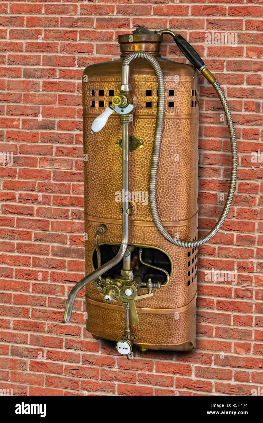 Vintage Gas Wasser Heizung mit Dusche auf der Backsteinmauer. Retro Durchlauferhitzer mit Tippen. Stockfoto