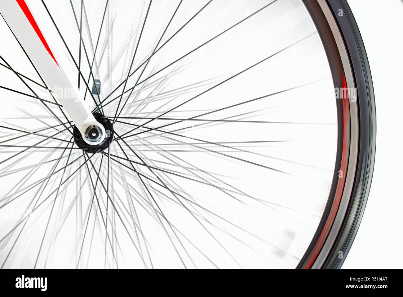Das Vorderrad der Fahrrad dreht sich schnell auf einem weißen Hintergrund. Detail der Road Bike während dreht. Stockfoto