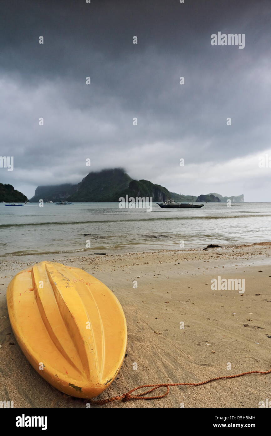 Gelbe fiberglas Kajak kopfüber am Strand gestrandet - gehen in einem verregneten Morgen festgemacht, die sie daran hindern, Meer zum Fischen und zu Stockfoto