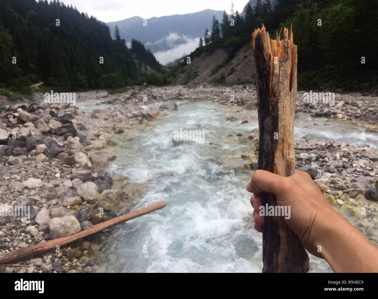 Wanderer mit Wandern Stick an einem Wild Mountain River suchen Stockfoto