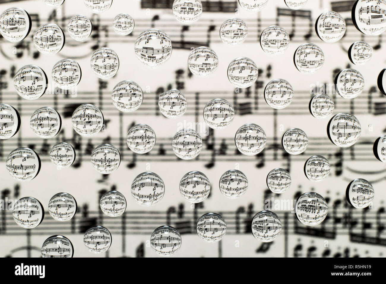 Musikalische Notation in Tropfen Wasser auf einem Hintergrund von verschwommenes Bild von Notizen Stockfoto