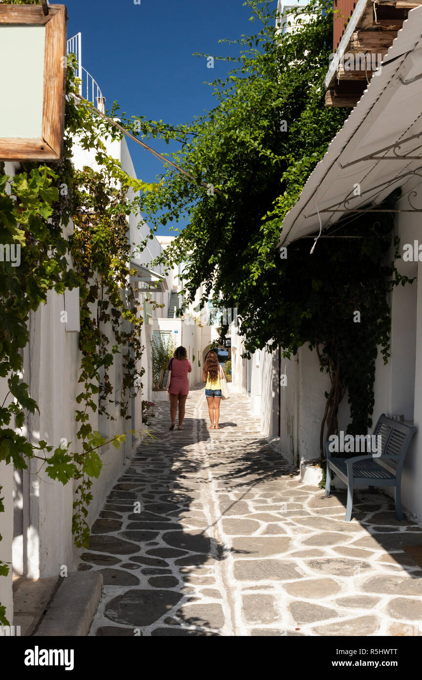 Zwei weibliche Touristen schlendern Sie entlang einer engen Gasse auf der Insel Paros, Griechenland. Stockfoto