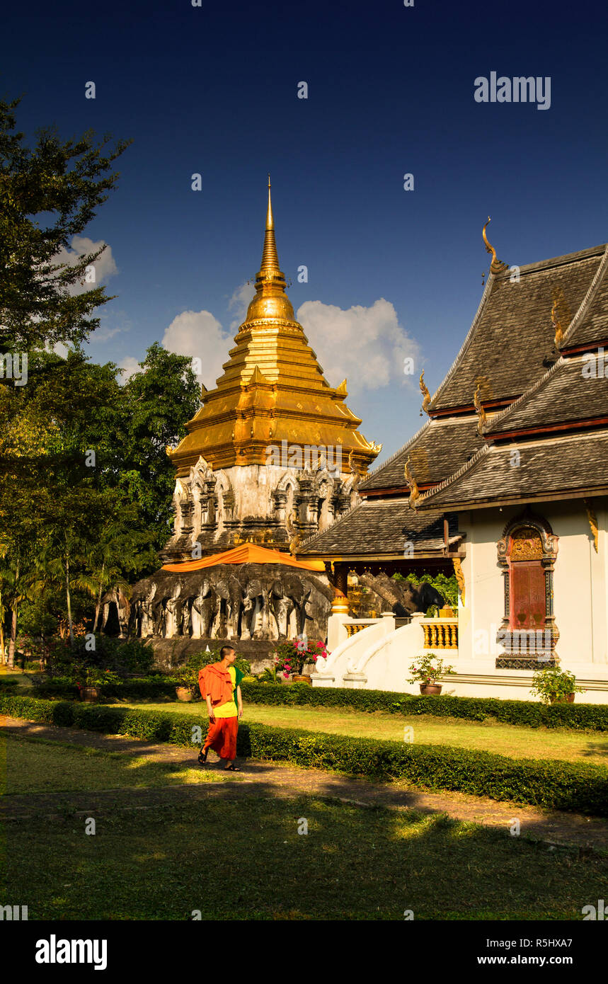 CHIANG MAI, THAILAND - Januar 13, 2017: Ein Mönch gekleidet in traditionelle Orange kleid Spaziergänge entlang der Tempel hof auf einem hellen, sonnigen Tag. Stockfoto