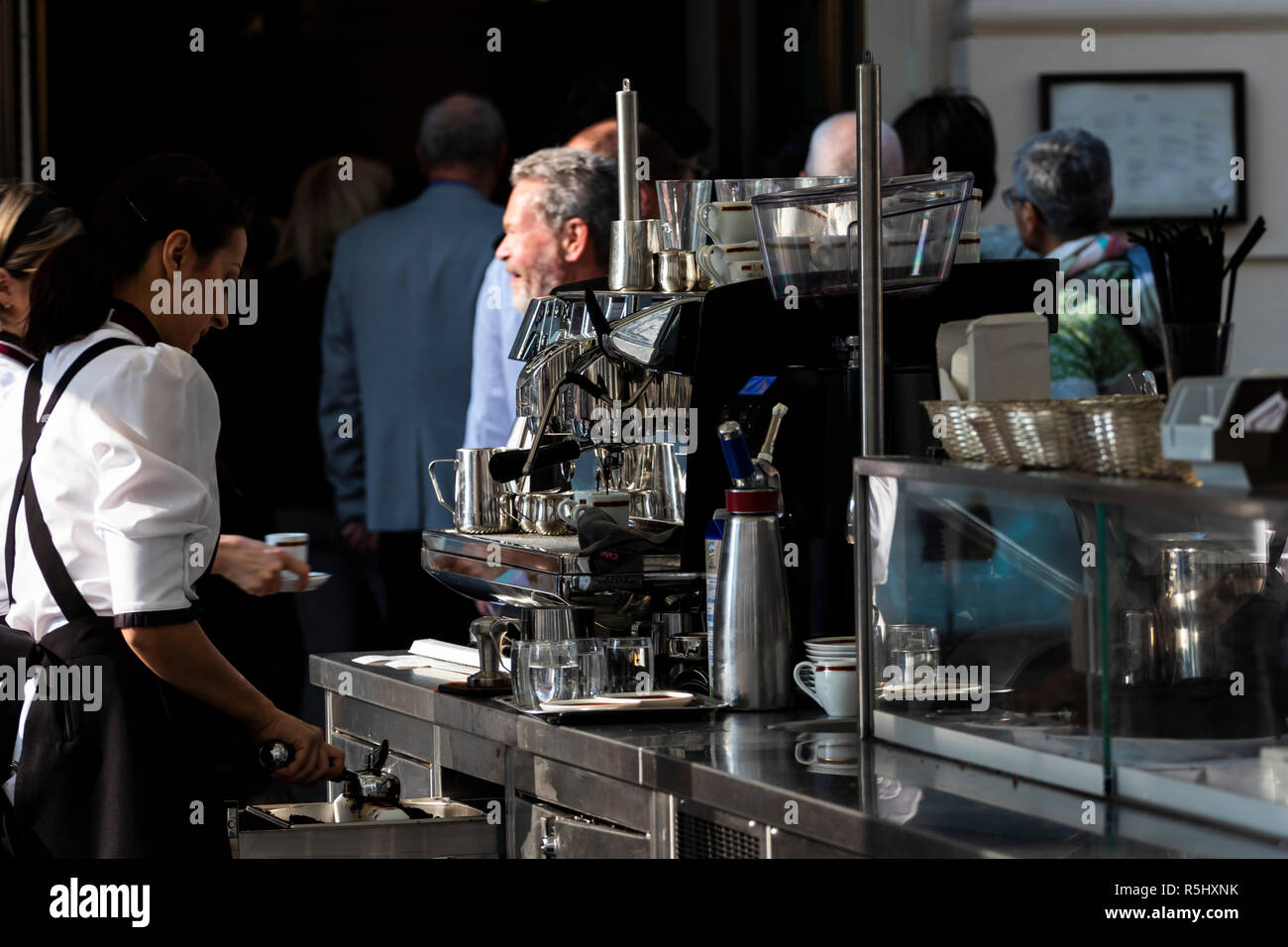 Wien, Österreich - 19. Oktober 2018: Kellnerin macht Kaffee hinter einem Chrom Kaffeemaschine in ein Café im Freien. Stockfoto