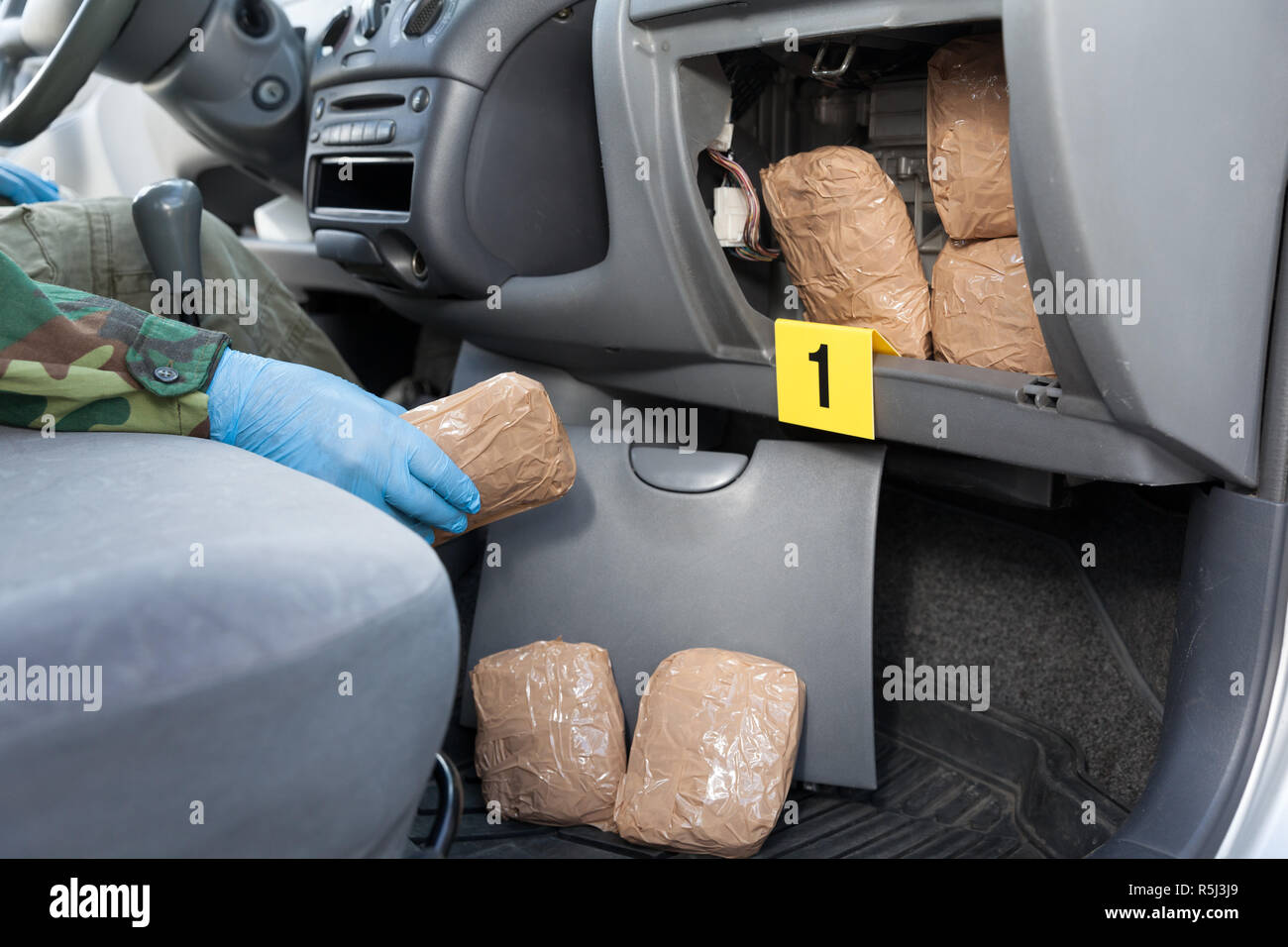 Polizeioffizier holding Droge Paket im Geheimfach in einem Auto gefunden Stockfoto