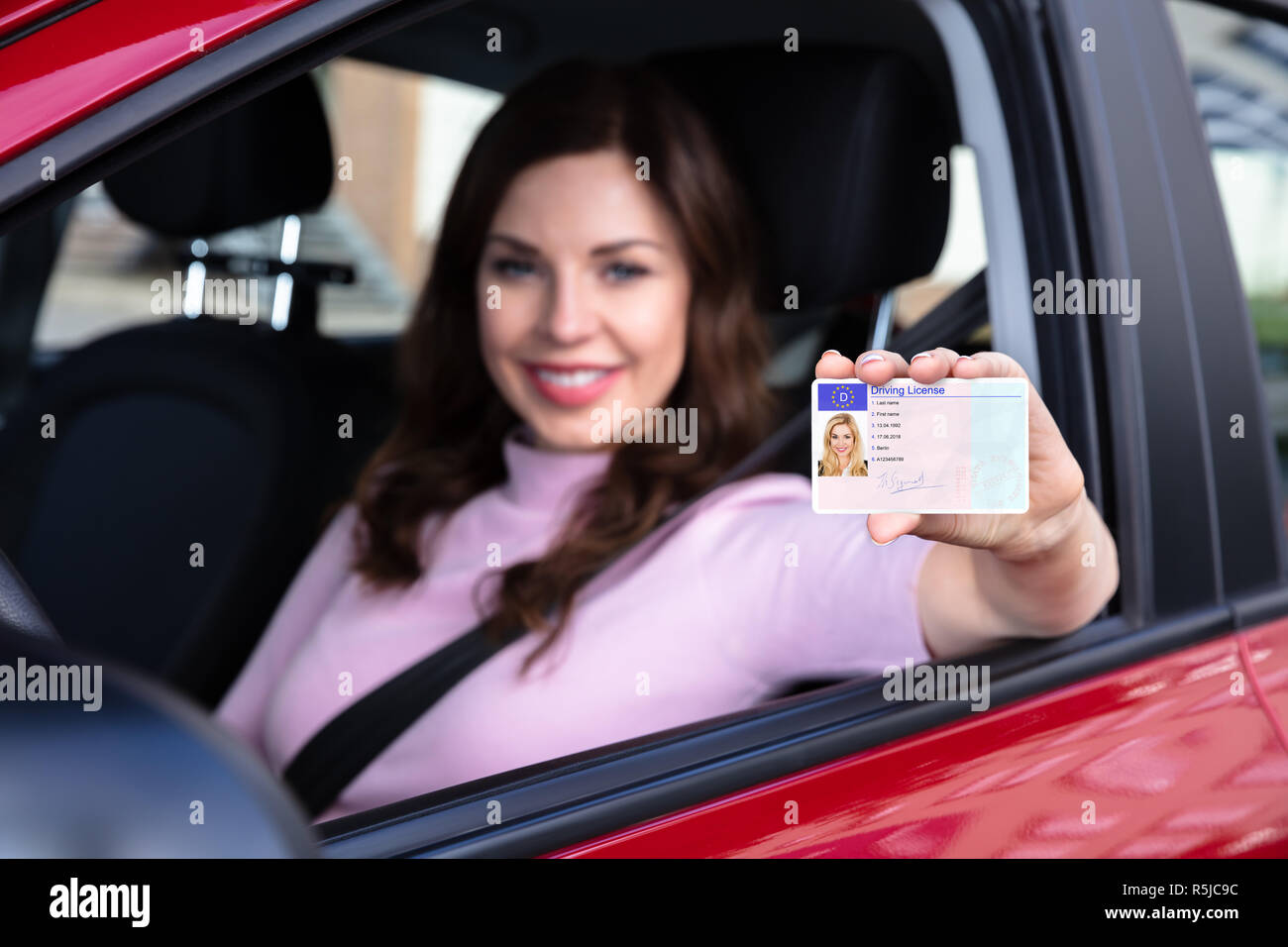 Nahaufnahme einer Frau, Führerschein aus dem offenen Autofenster Stockfoto