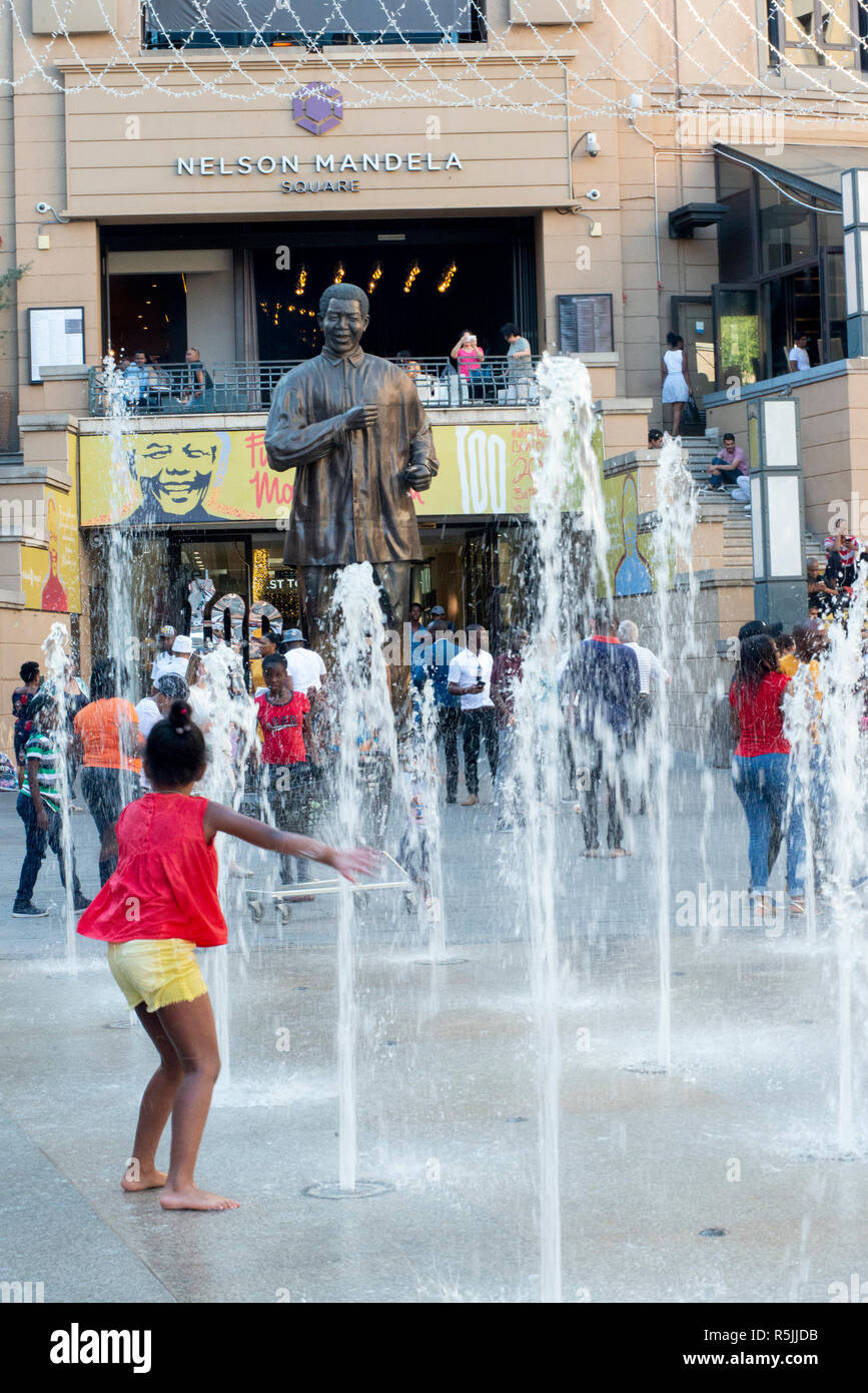 Johannesburg, Südafrika, 1. Dezember 2018. Kinder spielen in den Brunnen in der Nähe der Statue in Nelson Mandela Nelson Mandela Square in Sandton. Südafrika ist derzeit die Feier des 100. Jahrestages der Madiba Geburt. Credit: Eva-Lotta Jansson/Alamy leben Nachrichten Stockfoto