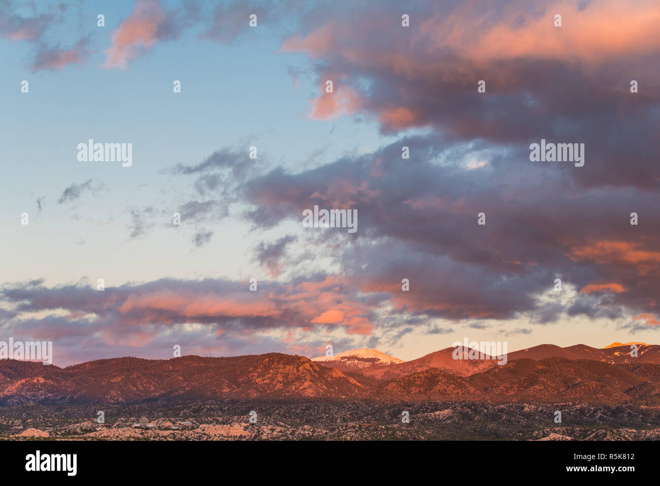 Dramatische, wunderschönen Sonnenuntergang wirft lila und orange Farben auf Wolken und Berge über eine Nachbarschaft in Tesuque, in der Nähe von Santa Fe, New Mexico Stockfoto