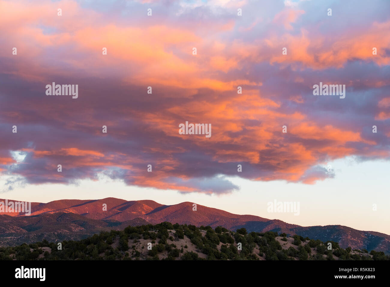 Dramatische, wunderschönen Sonnenuntergang wirft lila und orange Farben auf Wolken und der Sangre de Cristo Mountains in der Nähe von Santa Fe, New Mexico Stockfoto