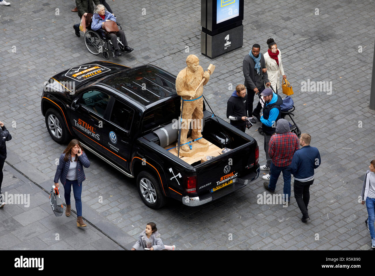 Das Stadtzentrum von Liverpool Liverpool One noch Kettensäge Unternehmen Förderung mit einem geschnitzten eine Holding ax auf der Rückseite eines VW Pickup Truck geschnitzt Stockfoto