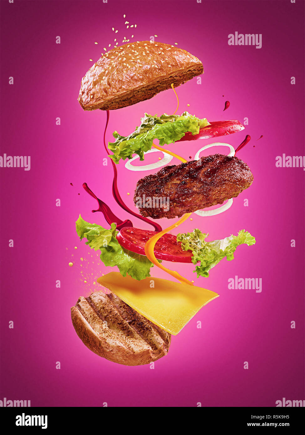 Die Hamburger mit fliegenden Zutaten auf lila Hintergrund Stockfoto