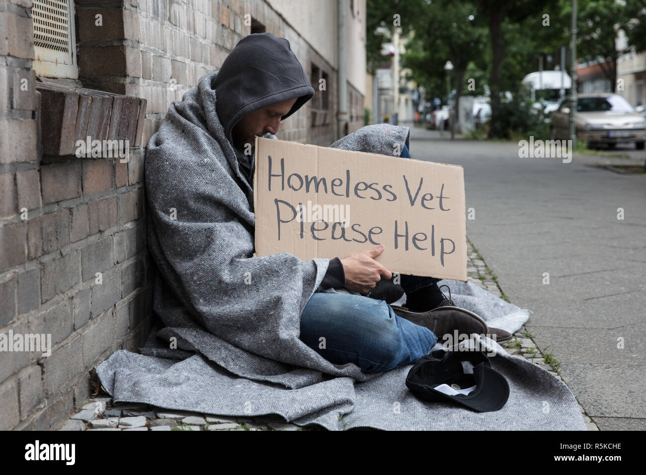 Männliche Obdachlose sitzen auf der Straße um Hilfe zu bitten Stockfoto