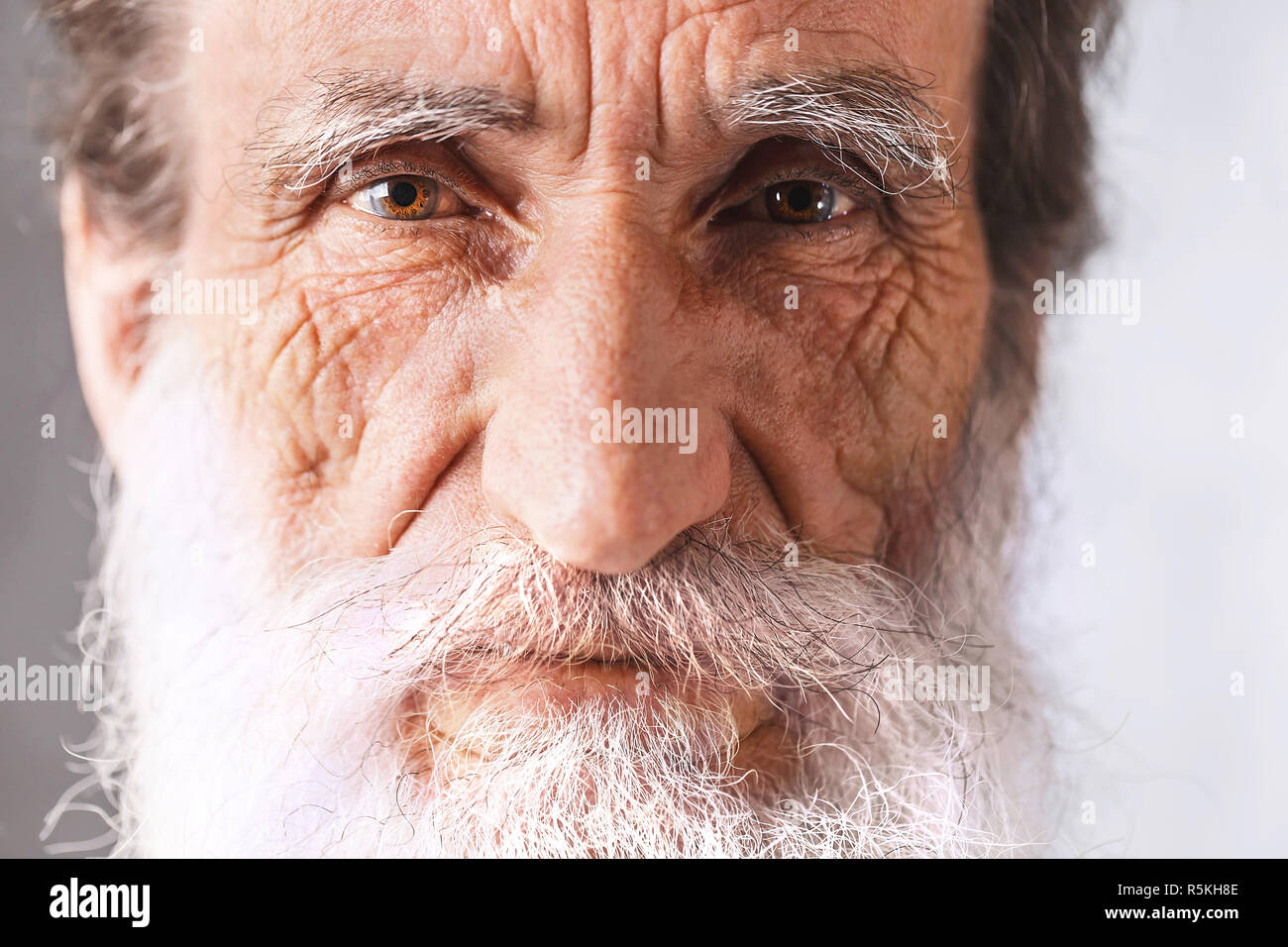 Porträt des zeitgenössischen fröhliche Bärtigen älteren Mann mit Falten im weißen Hemd auf dem grauen Hintergrund, moderne Technik, Kommunikation Konzept Stockfoto