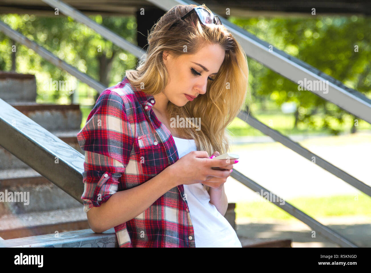 Junge schöne Blondine hipster Girl schreiben auf Smart Phone in der Stadt, Jugend Kommunikationskonzept, halb Körper Stockfoto