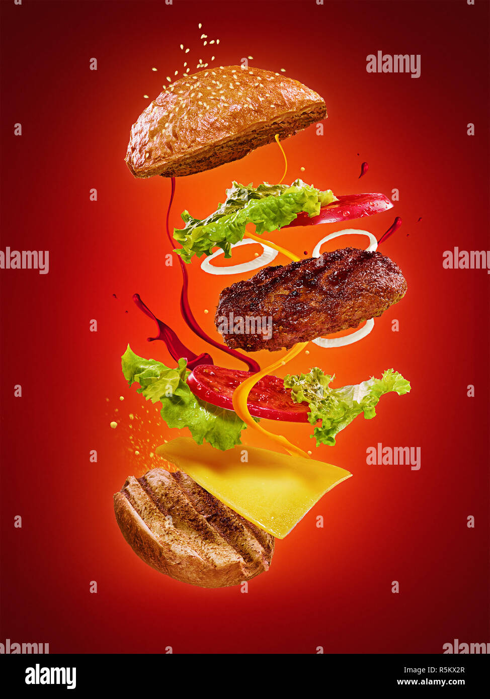 Die Hamburger mit fliegenden Zutaten auf rotem Hintergrund Stockfoto