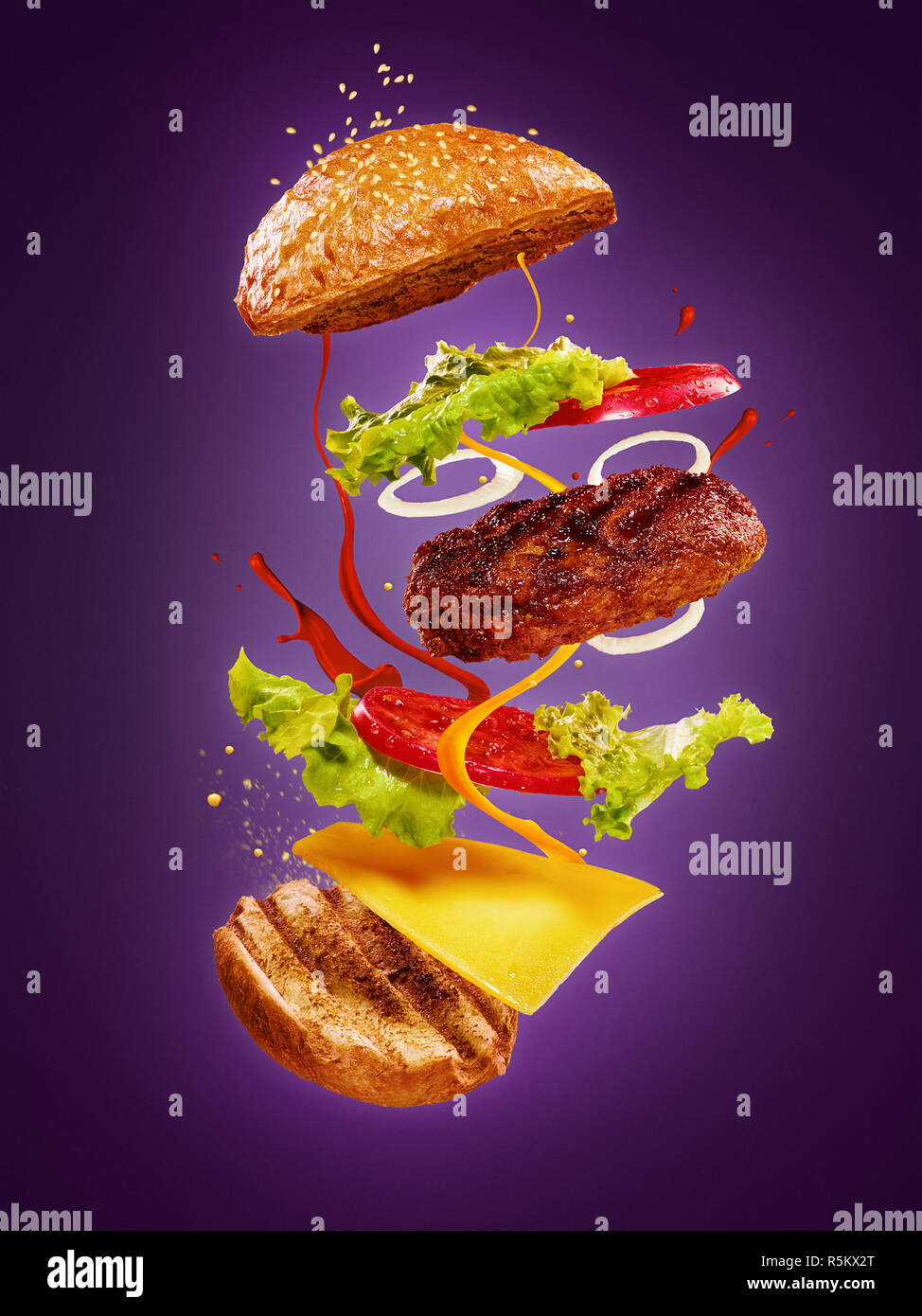 Die Hamburger mit fliegenden Zutaten auf lila Hintergrund Stockfoto