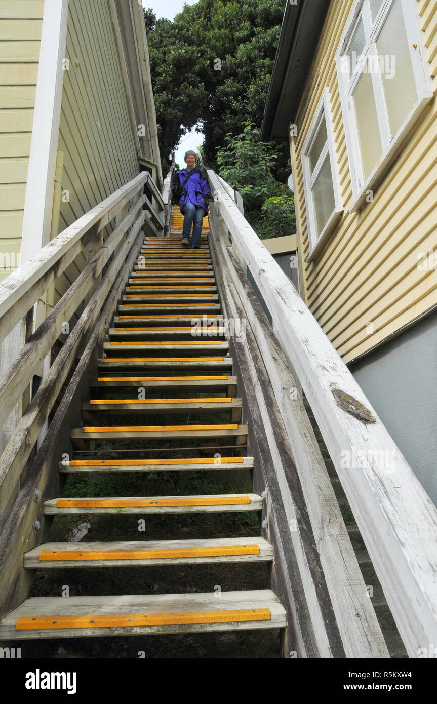 Eine Frau steigt eine lange und steile Treppe zwischen zwei Häusern Stockfoto